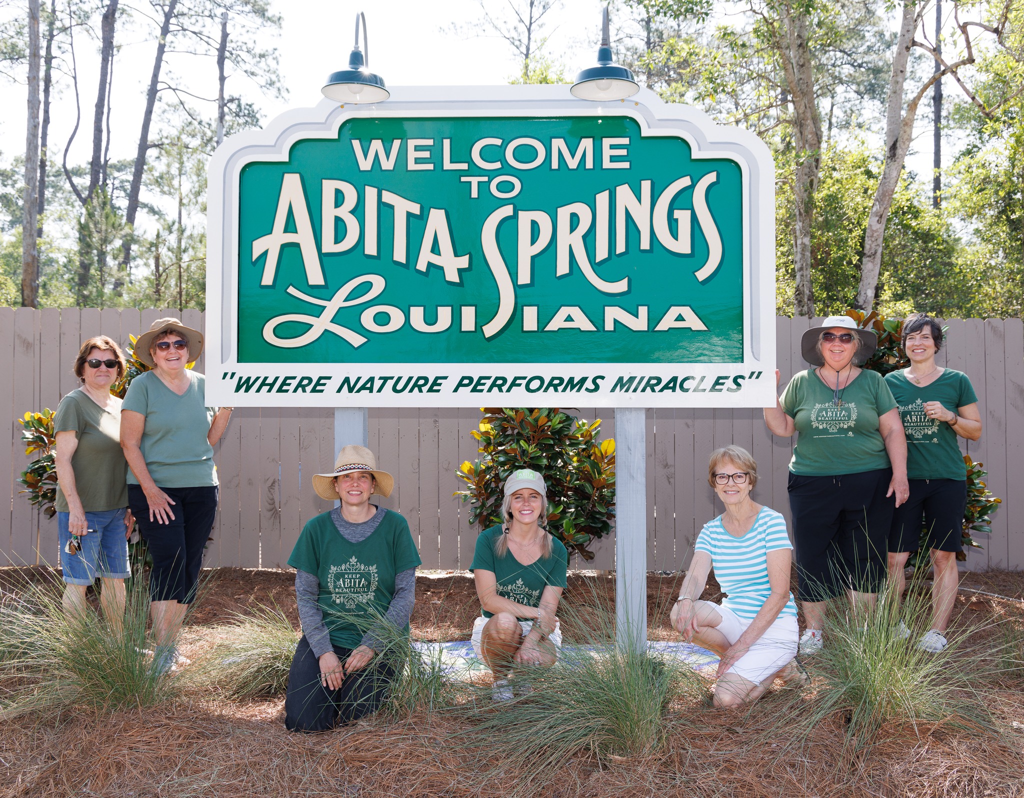 A group of women standing in front of the Welcome to Abita Springs sign.