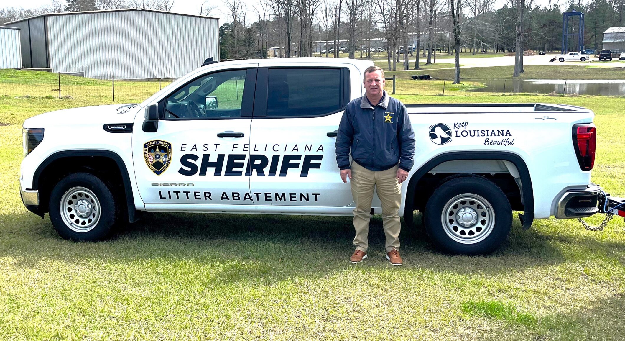 A man stands by a white East Feliciana Sheriff truck that reads "Litter Abatement."