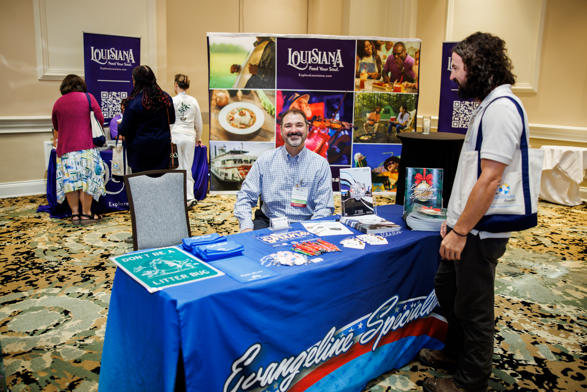 Sponsor exhibiting at conference. Smiling and interacting with guests.