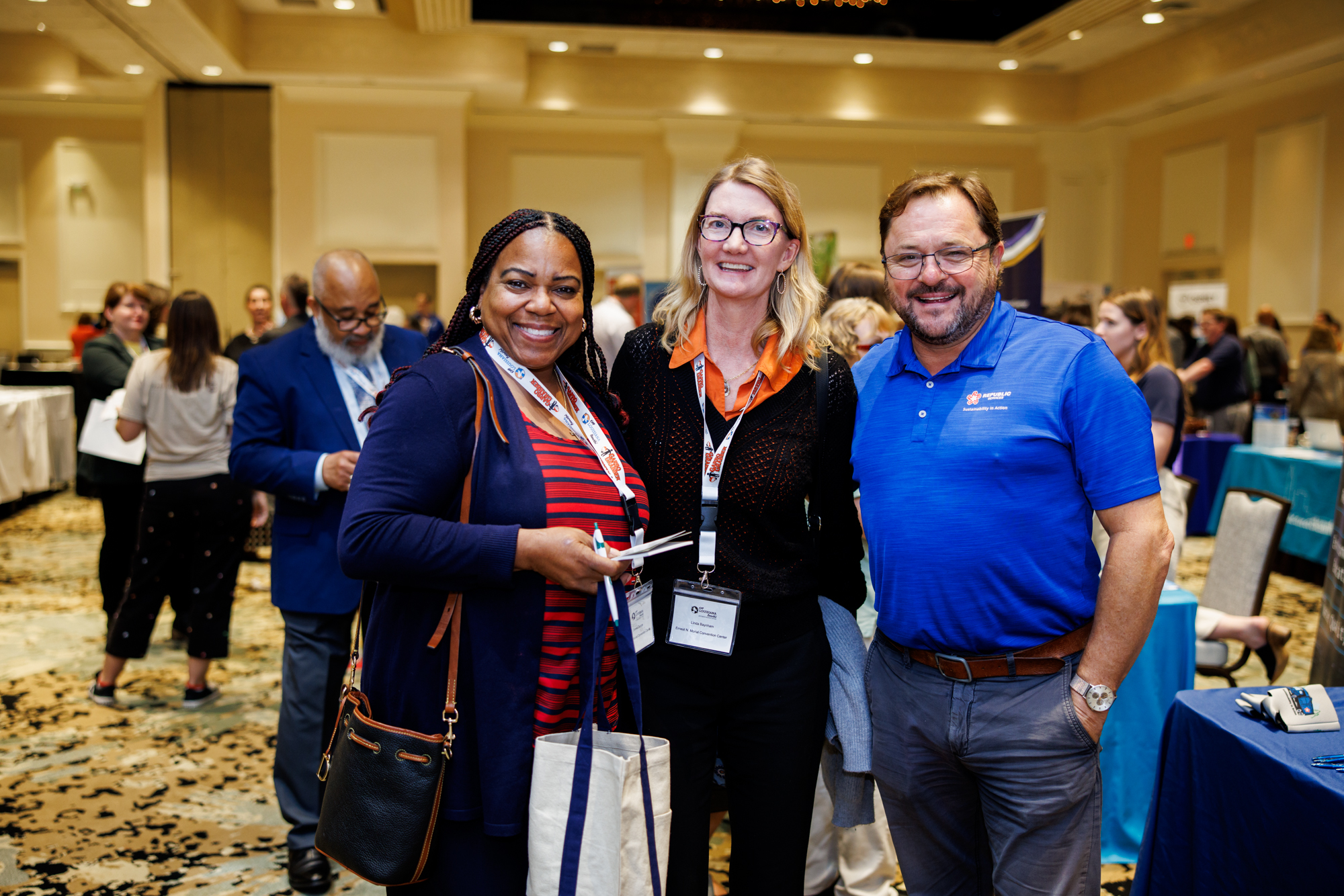 Three people smiling and mingling at conference